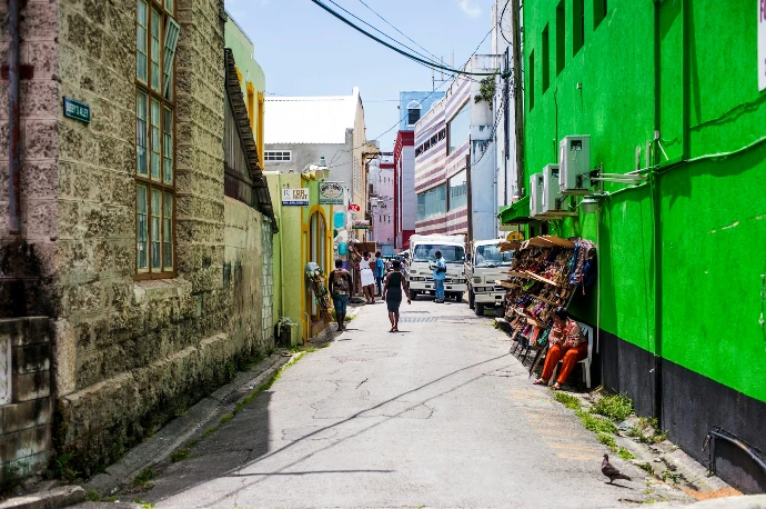 a man walking down a street next to a green building